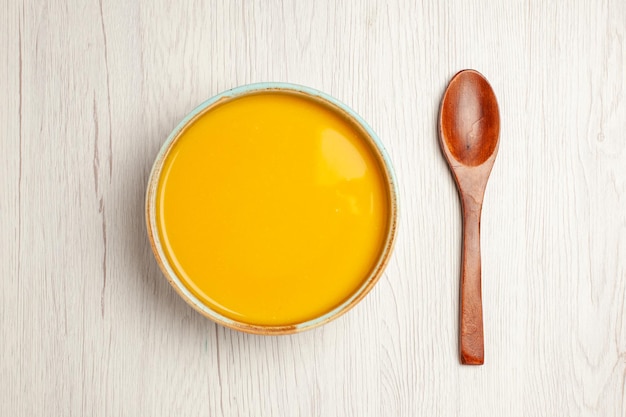 Vue de dessus délicieuse soupe à la crème soupe de couleur jaune sur un bureau blanc soupe sauce repas crème dîner plat