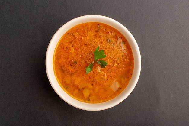 Vue de dessus de la délicieuse soupe à l'intérieur de la plaque sur une surface sombre