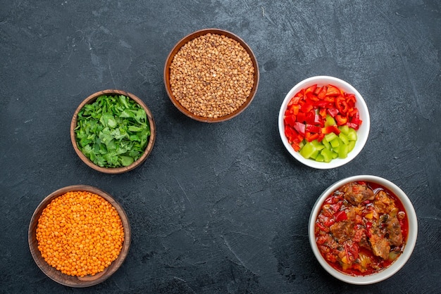 Vue de dessus une délicieuse soupe de légumes avec du sarrasin cru et des légumes verts sur l'espace gris