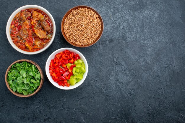 Vue de dessus une délicieuse soupe de légumes avec du sarrasin cru et des légumes verts sur l'espace gris