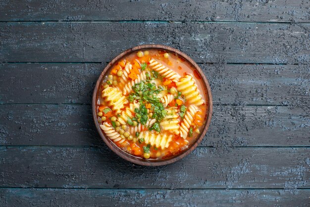 Vue de dessus une délicieuse soupe de pâtes avec des légumes verts et des légumes à l'intérieur de la plaque sur le plat de bureau sombre soupe de pâtes italiennes repas dîner