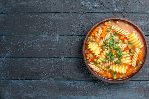 Vue de dessus une délicieuse soupe de pâtes avec des légumes verts et des légumes à l'intérieur de la plaque sur le plat de bureau sombre soupe de pâtes italiennes sauce dîner