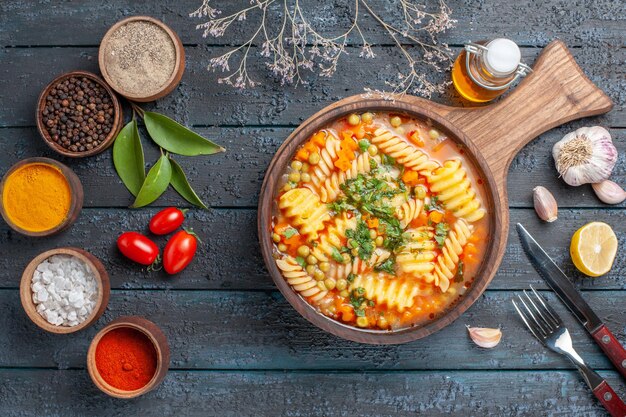 Photo gratuite vue de dessus délicieuse soupe de pâtes à partir de pâtes italiennes en spirale avec assaisonnements sur un bureau bleu foncé soupe de pâtes plat de couleur dîner cuisine