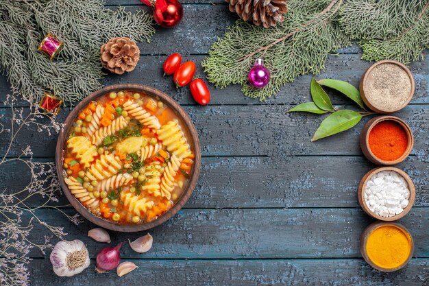 Vue de dessus délicieuse soupe de pâtes à partir de pâtes italiennes en spirale sur un plat de couleur de pâtes à soupe de cuisine rustique bleu foncé