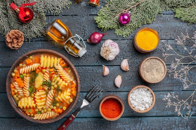 Photo gratuite vue de dessus délicieuse soupe de pâtes à partir de pâtes italiennes en spirale avec des verts sur un sol bleu foncé cuisine soupe de pâtes dîner plat de couleur