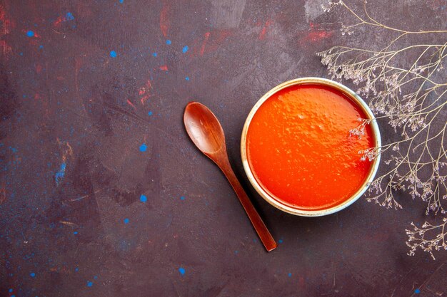 Vue de dessus délicieuse soupe de tomate cuite à partir de tomates fraîches sur fond sombre sauce repas plat de tomate soupe