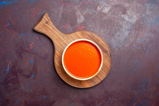Vue de dessus délicieuse soupe de tomate cuite à partir de tomates rouges fraîches sur fond sombre soupe de tomate sauce plat de repas