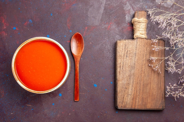 Vue de dessus délicieuse soupe de tomates cuite à partir de tomates fraîches sur un plat de bureau sombre sauce repas soupe de tomates