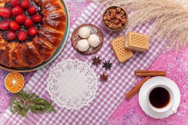 Vue de dessus délicieuse tarte aux fraises avec gaufres et tasse de thé sur rose