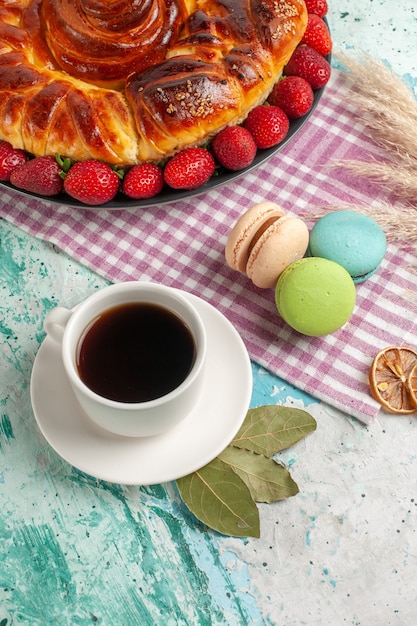 Vue de dessus délicieuse tarte aux fraises rouges et tasse de thé sur la surface bleue