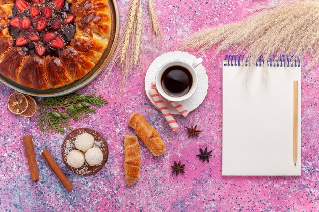 Vue de dessus délicieuse tarte aux fraises avec une tasse de thé sur le rose