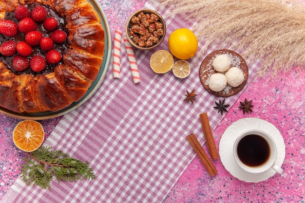 Vue de dessus délicieuse tarte aux fraises avec une tasse de thé sur le rose