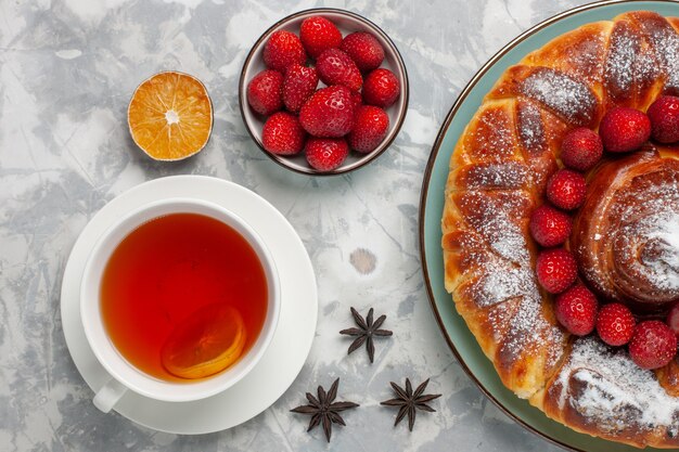 Vue de dessus délicieuse tarte aux fraises avec une tasse de thé sur la surface blanche gâteau tarte biscuit thé au sucre sucré cuire