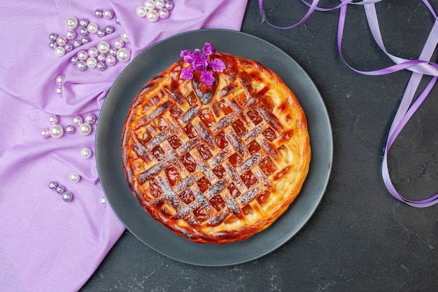 Vue de dessus délicieuse tarte aux fruits avec de la confiture à l'intérieur de la plaque sur une table sombre