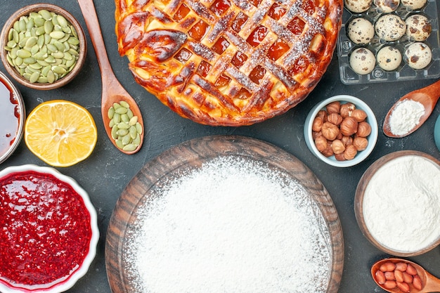 Vue de dessus délicieuse tarte aux fruits avec des noix de confiture et de la farine sur la tarte au dessert sombre pâte à gâteau au thé sucré biscuit cuire au sucre