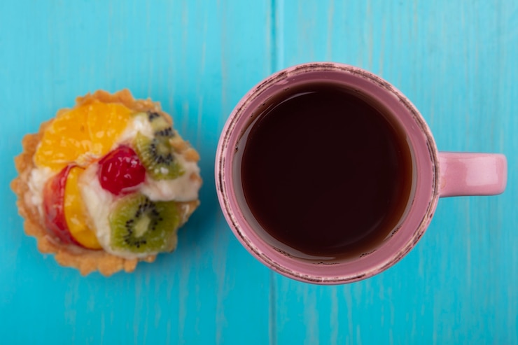 Photo gratuit vue de dessus de la délicieuse tarte aux fruits avec une tasse de thé sur un fond en bois bleu