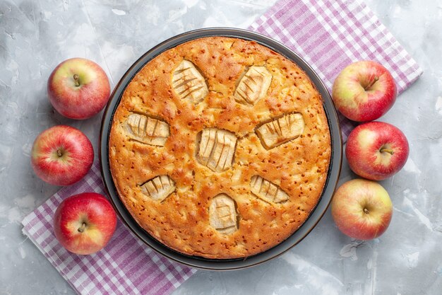 Vue de dessus délicieuse tarte aux pommes sucrée cuite au four avec des pommes sur le bureau blanc