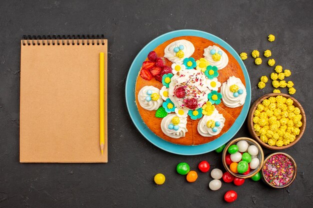 Vue de dessus d'une délicieuse tarte à la crème avec des bonbons dans l'obscurité