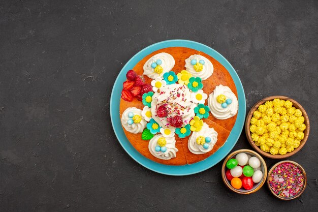 Vue de dessus d'une délicieuse tarte à la crème avec des bonbons sur fond noir