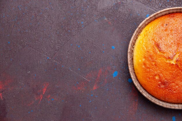 Vue de dessus délicieuse tarte ronde douce cuire au four sur un fond sombre gâteau biscuit tarte sucrée pâte à thé au sucre