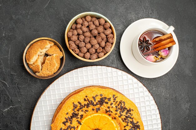 Vue de dessus délicieuse tarte sucrée avec une tasse de thé sur une surface sombre biscuit biscuit dessert tarte au gâteau au thé