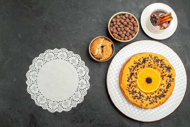 Vue de dessus délicieuse tarte sucrée avec une tasse de thé sur une surface sombre biscuits tarte biscuit dessert gâteau au thé