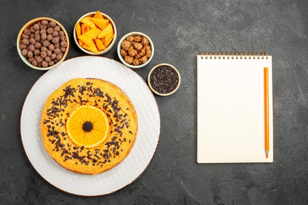 Vue de dessus délicieuse tarte sucrée avec des tranches d'orange sur la surface grise biscuit dessert tarte sucrée gâteau thé