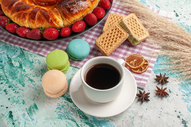 Vue de dessus délicieuse tarte avec tasse de thé et fraises rouges fraîches sur la surface bleue