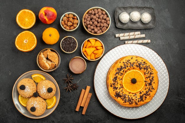 Vue de dessus une délicieuse tarte avec des tranches d'orange et des biscuits sur une surface sombre, un biscuit au thé, un dessert aux fruits, un gâteau à la tarte