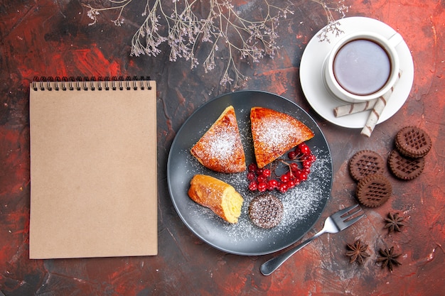 Vue de dessus délicieuse tarte en tranches avec une tasse de thé sur le gâteau de table sombre thé à tarte sucrée