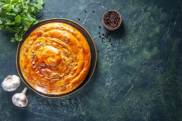 Vue de dessus d'une délicieuse tarte à la viande avec des ingrédients sur une surface sombre