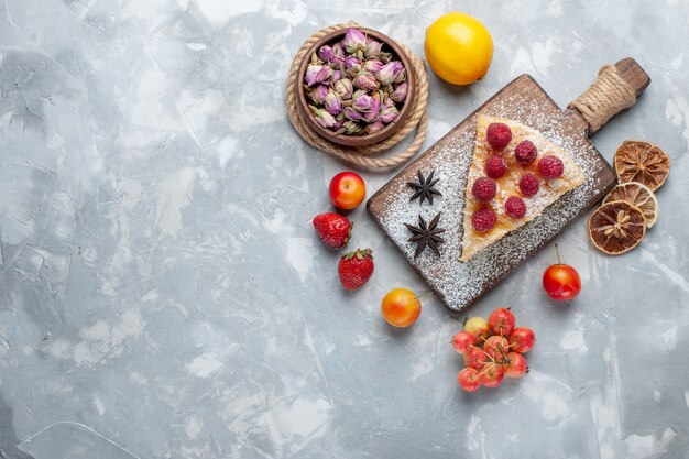 Vue de dessus délicieuse tranche de gâteau au citron et fruits sur un bureau léger biscuit gâteau au sucre sucré cuire au four