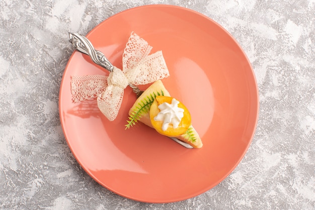 Vue de dessus délicieuse tranche de gâteau avec de la crème et des abricots frais à l'intérieur de la plaque rose sur le fond clair gâteau de pâte au sucre sucré