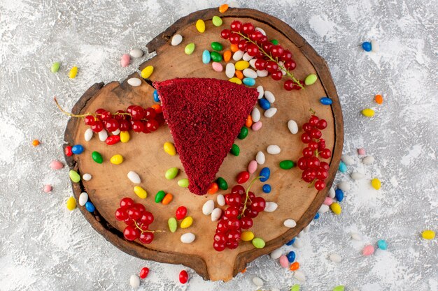 Vue de dessus délicieuse tranche de gâteau à la crème et aux fruits sur le bureau en bois avec des bonbons multicolores gâteau biscuit sweet goodie