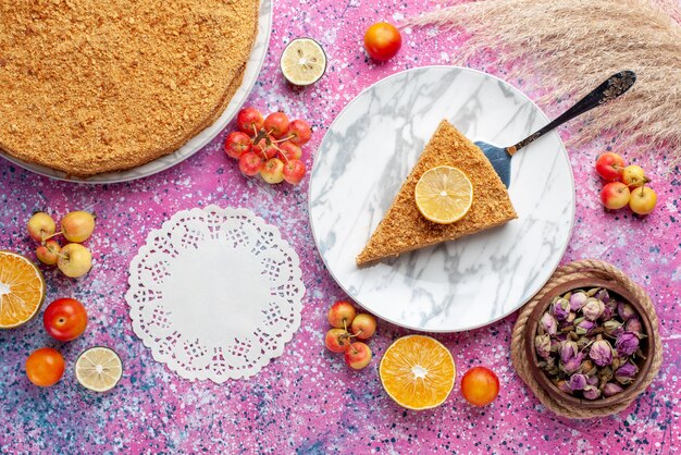 Vue de dessus délicieuse tranche de gâteau rond à l'intérieur de la plaque avec des fruits frais sur le bureau rose vif gâteau tarte biscuit sweet bake