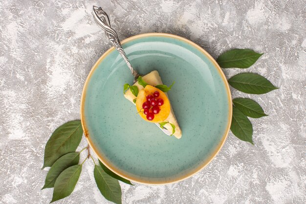 Vue de dessus délicieuse tranche de gâteau avec tranche d'abricot à l'intérieur de la plaque verte sur le bureau léger gâteau biscuit pâte sucrée cuire au four