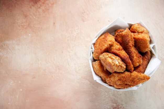 Vue de dessus de délicieuses ailes de poulet à l'intérieur d'une assiette avec des serviettes sur une surface claire