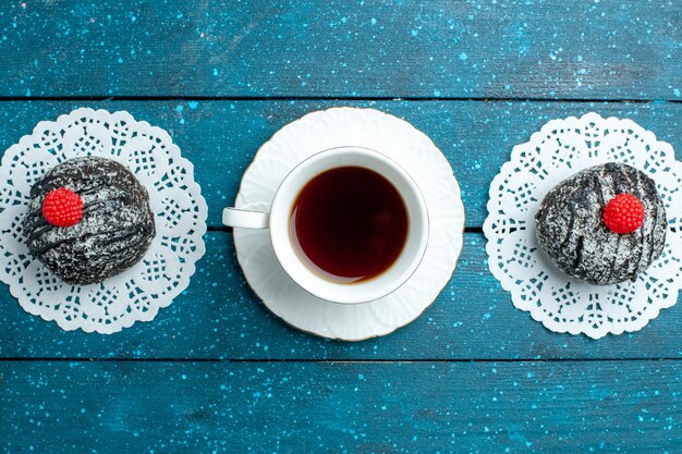 Vue de dessus de délicieuses boules de chocolat avec une tasse de thé sur le bureau rustique bleu gâteau au thé biscuit biscuit doux