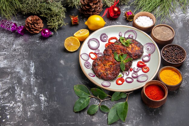 Vue de dessus de délicieuses côtelettes avec des rondelles d'oignon sur le plat de fond gris repas de viande