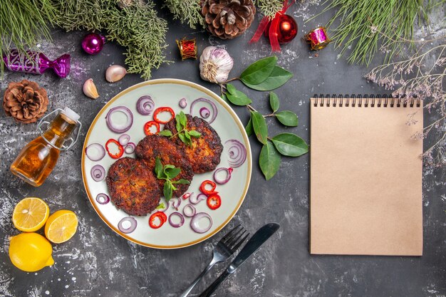 Vue de dessus de délicieuses côtelettes avec des rondelles d'oignon sur le plat de viande de fond gris repas