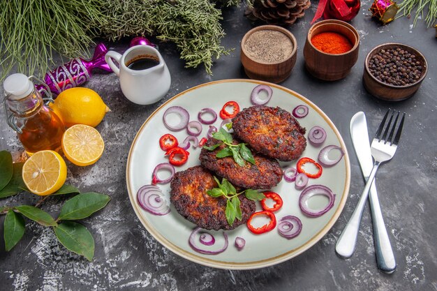 Vue de dessus de délicieuses côtelettes de viande avec des assaisonnements sur un plat de photo de repas au sol gris clair