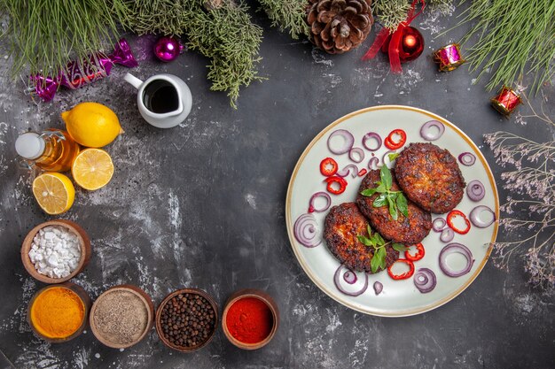 Vue de dessus de délicieuses côtelettes de viande avec assaisonnements sur le plat de photo repas fond gris clair