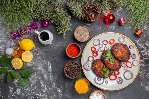 Vue de dessus de délicieuses côtelettes de viande avec assaisonnements sur le plat de photo repas fond gris clair