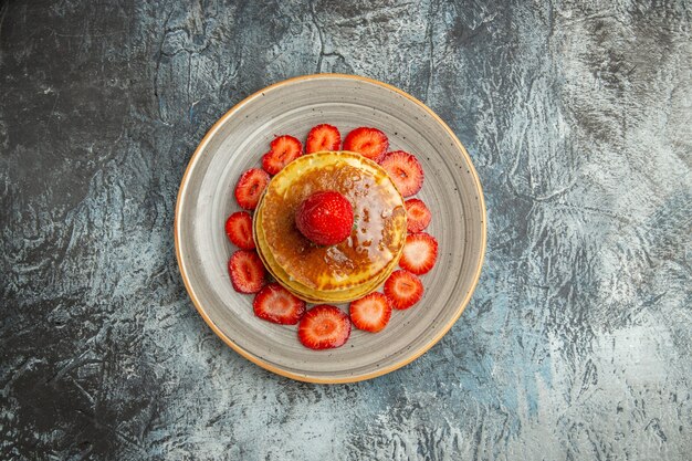 Vue de dessus de délicieuses crêpes au miel et aux fraises à la lumière