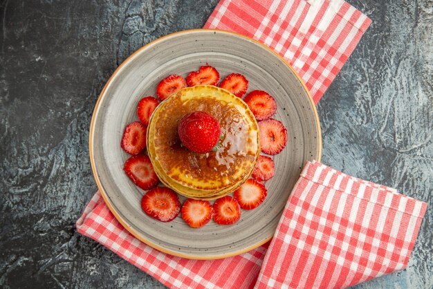 Vue de dessus de délicieuses crêpes au miel et aux fraises à la lumière