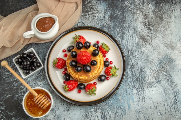 Vue de dessus de délicieuses crêpes au miel et aux fruits sur un gâteau aux fruits sucré de surface légère