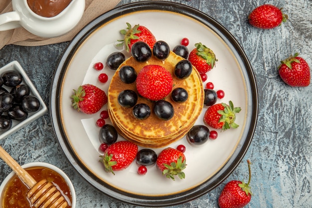 Vue de dessus de délicieuses crêpes au miel et aux fruits sur un gâteau aux fruits sucré de surface légère