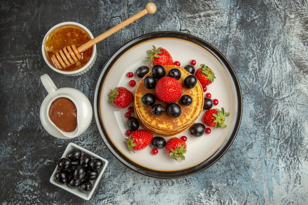 Vue de dessus de délicieuses crêpes au miel et aux fruits sur un gâteau de surface légère aux fruits sucrés