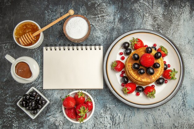 Vue de dessus de délicieuses crêpes au miel et aux fruits à la lumière