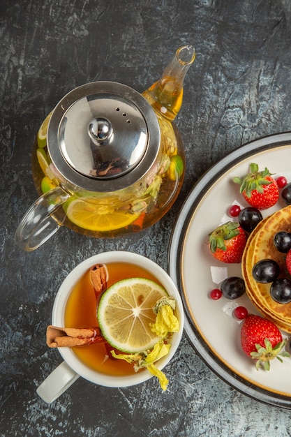 Photo gratuite vue de dessus de délicieuses crêpes aux fruits et au thé sur un bureau léger petit-déjeuner aux fruits sucrés